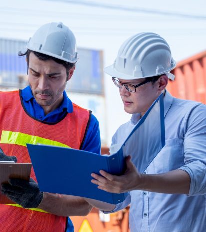 Foreman and cargo container worker discuss together with document in workplace area